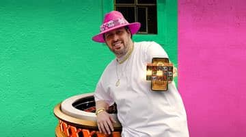 Dogge står framför ett roulettehjul och håller upp sin mobil där ett slotsspel visas på skärmen. På huvudet bär han en rosa hatt som är en av GoGo casinos signaturfärger.