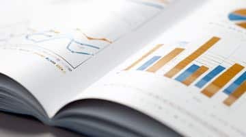 En ekonomisk rapport ligger uppslagen på ett bord. I rapporten syns grafer och stapeldiagram.